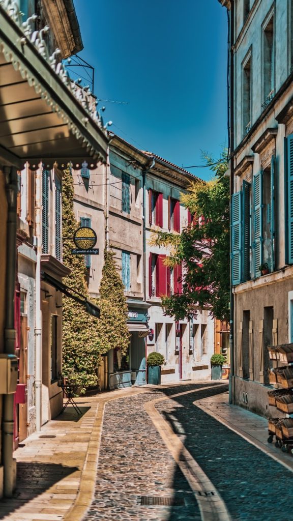 רחוב שטוף שמש בכפר בדרום צרפת מחוז פרובאנס. רחוב צר עם בתים צבעוניים ברחוב מרוצף בסגנון ישן.