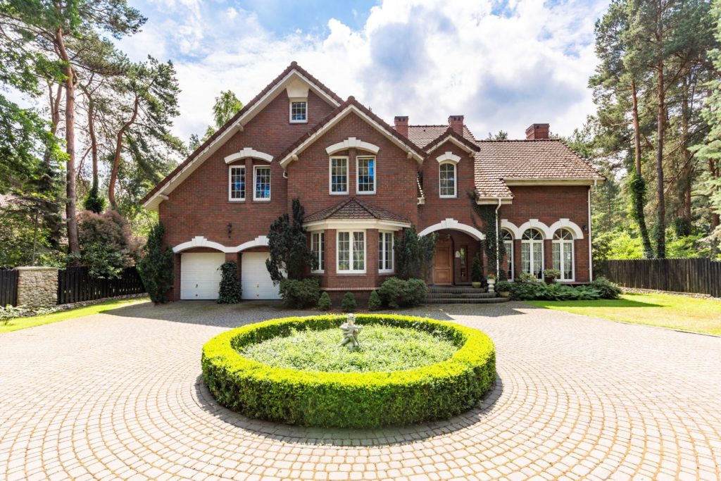 Beau manoir brun avec une allée et une fontaine.