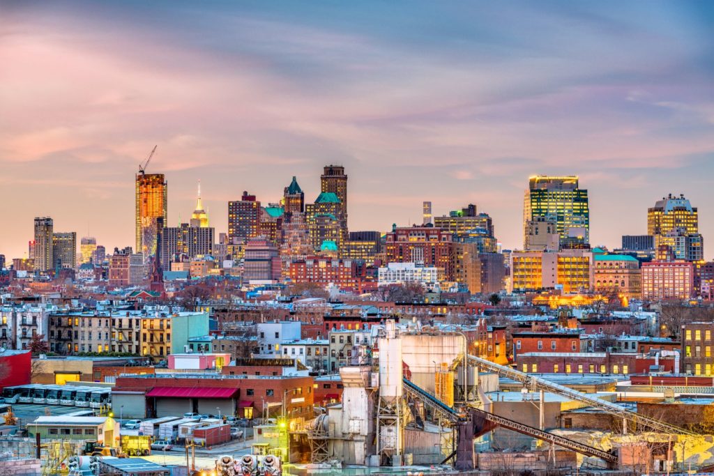 View of the NYC skyline at the back, with the Brooklyn skyline in front, during sunset.