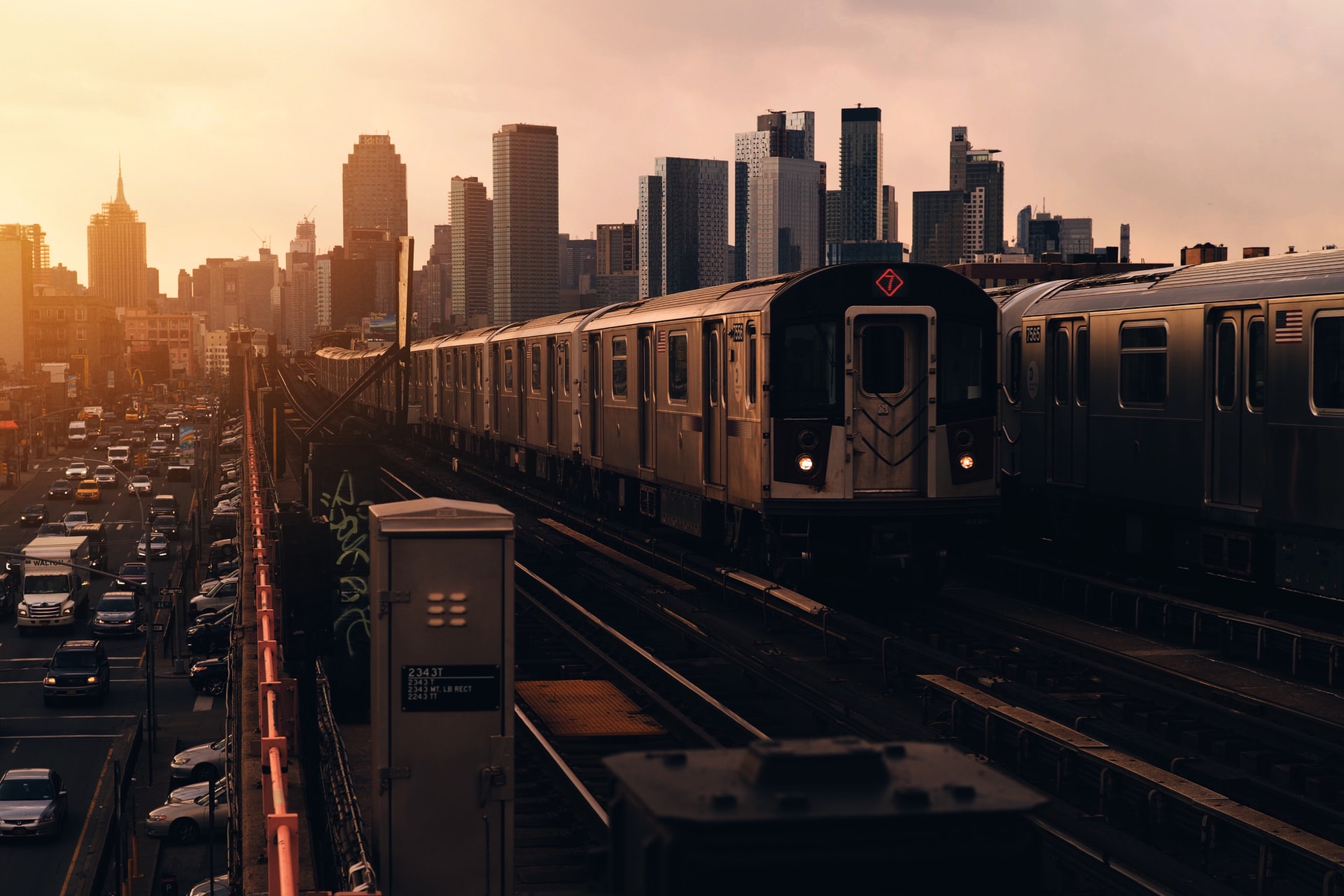 Vista da linha de metrô 7 Express em Queens, com o horizonte de Manhattan ao fundo durante o pôr do sol.