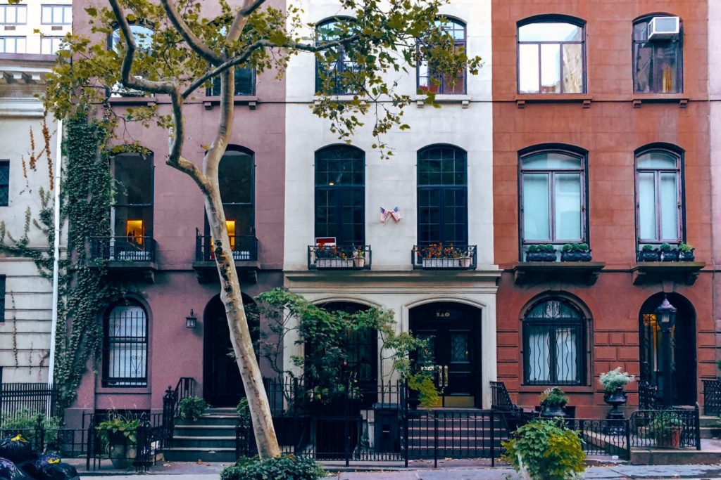 Moradias típicas de Nova York seguidas em uma rua tranquila com árvores.