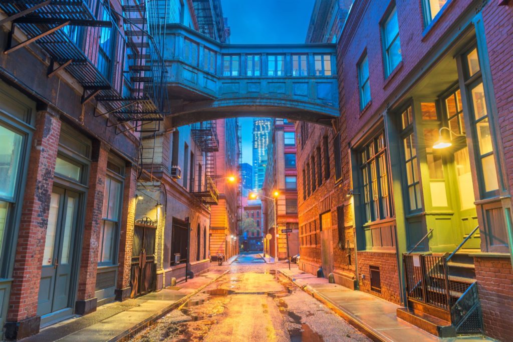 Vue nocturne d'une ruelle à TriBeCa, avec des lumières éclairant les porches sur les côtés.